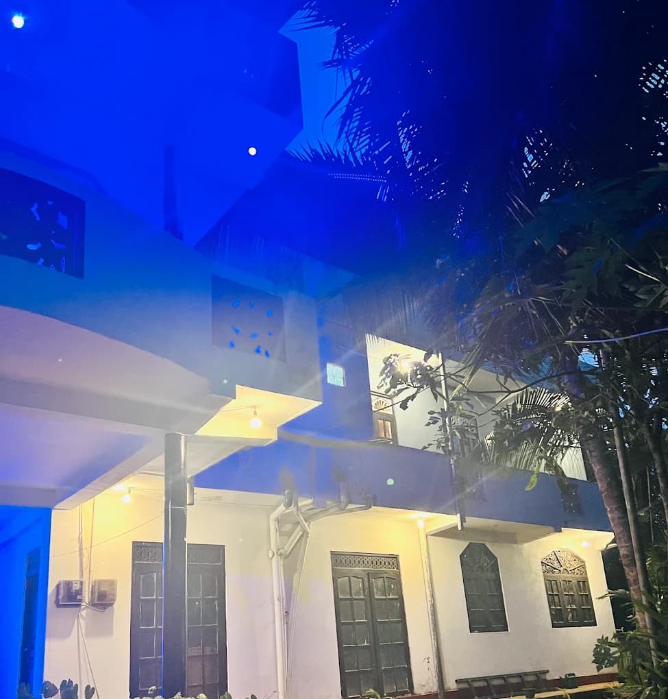 Guest house building lit at night among palms